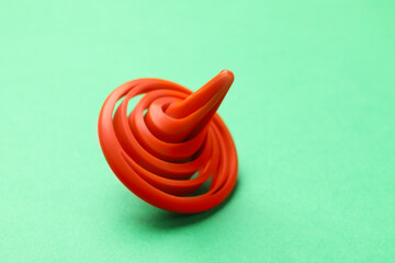 One orange spinning top on green background, closeup. Space for text