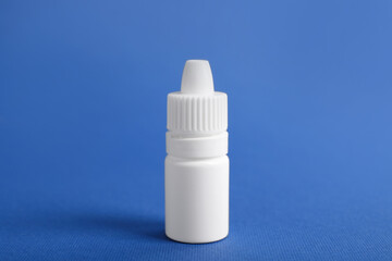Bottle of medical drops on blue background