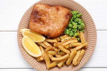 Tasty fish, chips, peas and lemon on white wooden table, top view