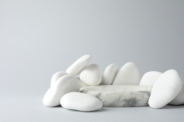 Presentation for product. Stone podium and pebbles on light grey background. Space for text
