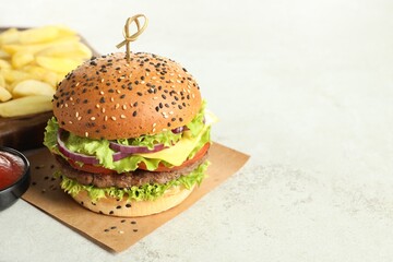 Burger with delicious patty and french fries on light table, closeup. Space for text