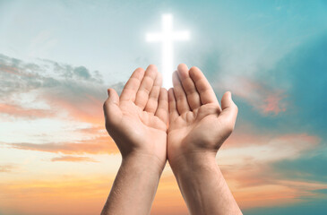 Religion. Christian man praying against sky with glowing cross, closeup