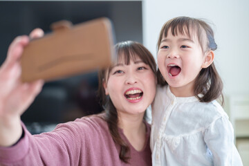 スマートフォンで自撮りをする親子　女の子とお母さん
