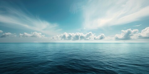 A calm ocean with a few clouds in the sky. The sky is blue and the water is clear