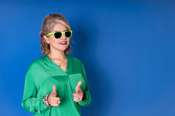 A woman in a green shirt is wearing sunglasses and pointing at something