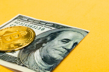 a bitcoin cryptocurrency on a hundred dollar bill torn in half on a yellow background, concept of currency crisis and web3