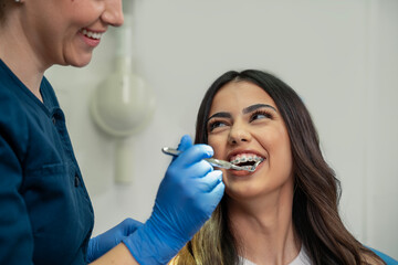 Closeup shot, cute young woman with dental braces smiling while her dentist doing check up 