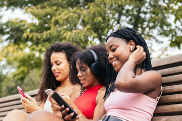 African American Friends Enjoying Summer Together using smartphone and listening to music