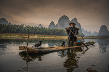 Sailing peacefully across a river, Guilin cormorant fishermen set out on river
