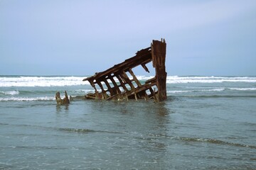 Metal frame of a ship washed up on the shore, a part of the Peter Iredale Shipwreck, with waves...