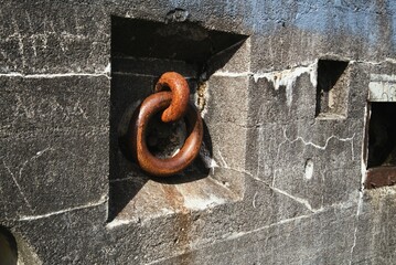 Close up angled view of massive iron ring inset in concrete wall. 