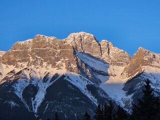Early morning mountain landscape of a mountain peak with fresh snow and a clear blue sky.