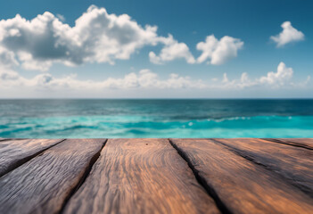 Wooden deck overlooking a vibrant turquoise ocean under a clear blue sky with fluffy clouds.