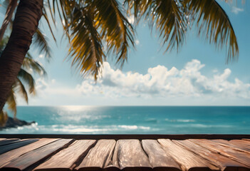 View of a tropical beach from a wooden deck, framed by palm trees, with a clear blue sky and shimmering ocean.