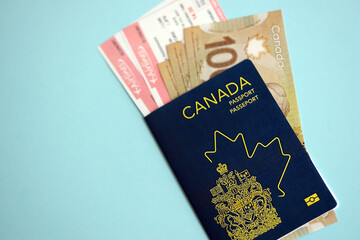 Fototapeta premium Canadian passport with money and airline tickets on blue background close up. Tourism and travel concept