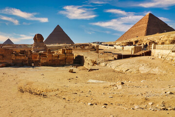 Magnificent scene of the the historic sights of Egypt -  3 Great Pyramids of Khufu,Khafre and Menkaure along with the Great Sphinx against bright blue skies on the Giza plateau at Cairo,Egypt - obrazy, fototapety, plakaty