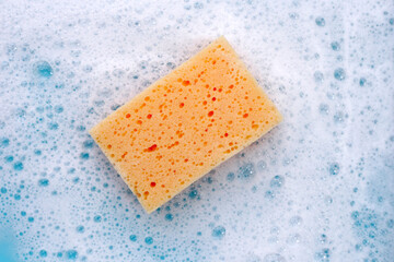 Cleaning sponge in foam of dishwashing liquid. Washing dishes concept