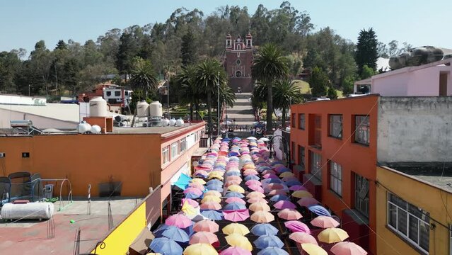 Volando sobre las calles de Metepec. Paraguas de colores colgados en una calle de un pueblo m&aacute;gico