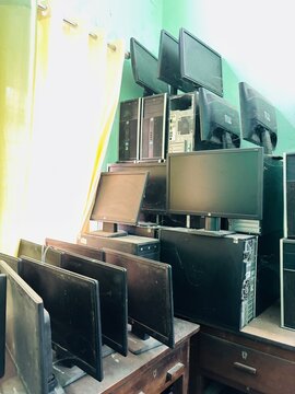 old computers and technology dumped in a room. A storage room cluttered with outdated computers, obsolete electronics, and discarded technology from past decades, left abandoned and gathering 