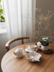 Aesthetic setting of the breakfast table - ceramic dishes, decor on a wooden round table in the living room - 787772793