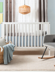 Serenely styled baby's bedroom highlighting a white modern crib, a plush gray rocker and a beige...