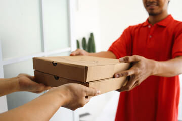 Delivery man in red uniform deliver two boxes of pizza to customer. Fast food delivery concept.