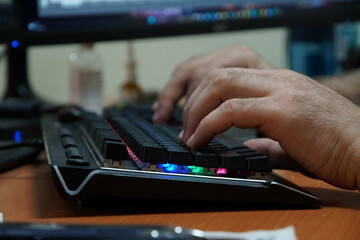 The hands of an adult man are typing on a computer keyboard. Close-up.