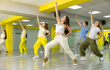 Trendy teenagers dancing hip-hop in studio, learn dance moves together, wearing stylish outfit