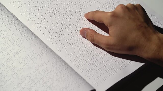 Close-Up of Hand Reading Braille Text on Paper