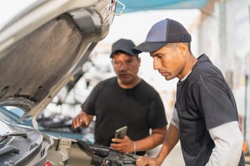 Team of mechanics examining the engine of a car