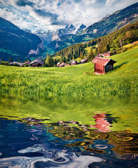 Majestic Swiss countryside reflected in the calm waters of small lake. Green summer scene of Wengen...