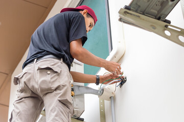 Technician connecting electric wires to install new air conditioning, repair service, and install...