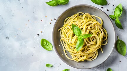 Pasta spaghetti with pesto sauce and fresh basil leaves in grey bowl light grey background - obrazy, fototapety, plakaty