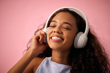 Happy girl, relax and listening to music with headphones for jazz or beats on a pink studio...