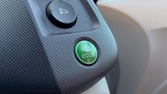 Finger pressing green eco mode button at auto panel. Safety concept