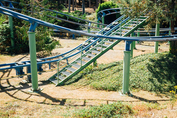 Manège à sensation. Petit train dans un parc d'attraction.  Manège à vitesse. Rails élevées pour un train. Rails en hauteur. Rampe et ascension d'un manège. Fête foraine dans un milieu naturel. 