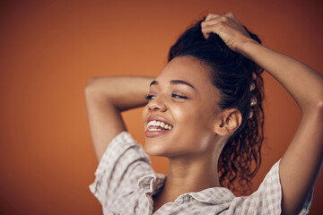 Washing, smile and woman with wet hair in studio with cosmetics, shampoo or treatment on orange background. Haircare, model and scalp detox with growth, texture or cleaning, serum or gel application