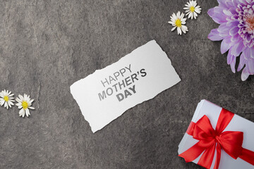 Paper with Happy Mother's Day text and a gift box on a black background. Mothers day concept - 787868336
