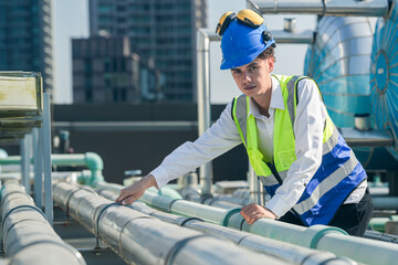 Technical professional evaluating air conditioning units on top of an urban high-rise.