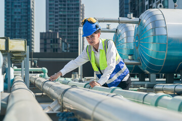 Technical professional evaluating air conditioning units on top of an urban high-rise.