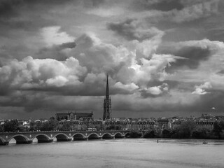 Scenic view of Bordeaux river bridge with St Michel cathedral and storm sky, Bordeaux, France. High...