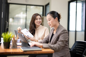 Engaged businesswoman presenting a colorful financial report during a collaborative meeting with a coworker in an office.