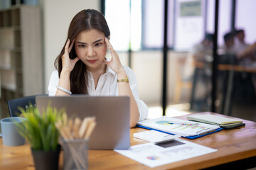 Concerned businesswoman in deep thought, facing work challenges while at her laptop in a busy...