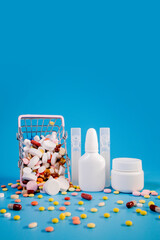 Buy and shopping medicine concept. Various capsules, tablets and medicine in the shopping cartt on a blue background. Creative idea for health care, health insurance and pharmaceutical company