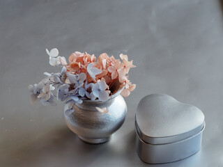 Dried flowers in vase with silver heart gift box, concept for birthday or Valentine's Day.
