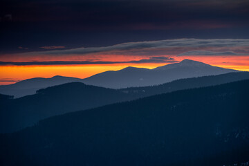 Dramatic sunrise in Beskids Mountains. View from Rysianka mountain to Babia Gora peak on the fire...