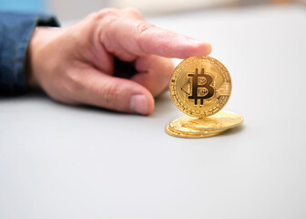 A hand is holding a bitcoin coin on a table