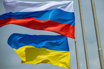 Russian and Ukrainian flags are waving with wind over blue sky. Low angle view. Dispute and conflict concept. Horizontal composition with copy space. - 787922365
