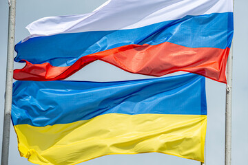Russian and Ukrainian flags are waving with wind over blue sky. Low angle view. Dispute and conflict concept. Horizontal composition with copy space. - 787923195