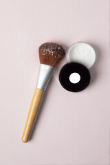 Make up wood brush with white loose powder on pink background, natural and eco cosmetic